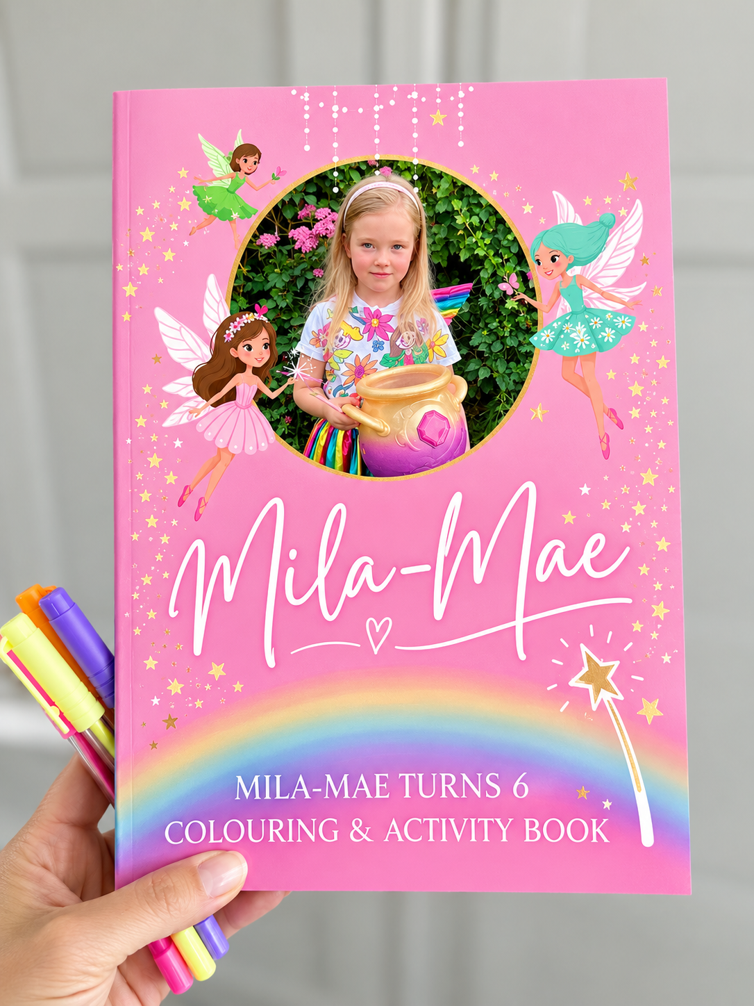 Mila-Mae's fairy colouring and activity book held up with pens